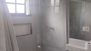 Une salle de bain dotée d’une douche à parois de verre, de toilettes et d’un lavabo avec un plan de travail en marbre.