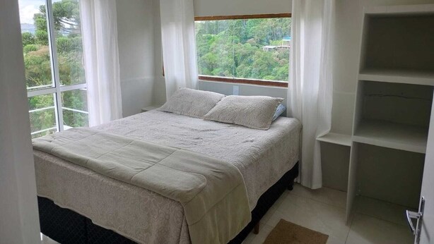 Une chambre à coucher avec un lit, une fenêtre avec des rideaux et une vue sur la verdure.