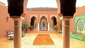 A courtyard with arches, a central rug, and a gate. - Residence Dar Lamia Marrakech : 1 Bedroom Villa  (Dar Caïd Layadi)