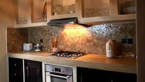 A kitchen with a gas stove, oven, and microwave. There are cabinets and a tiled backsplash. - Residence Dar Lamia Marrakech : 1 Bedroom Villa  (Dar Caïd Layadi)