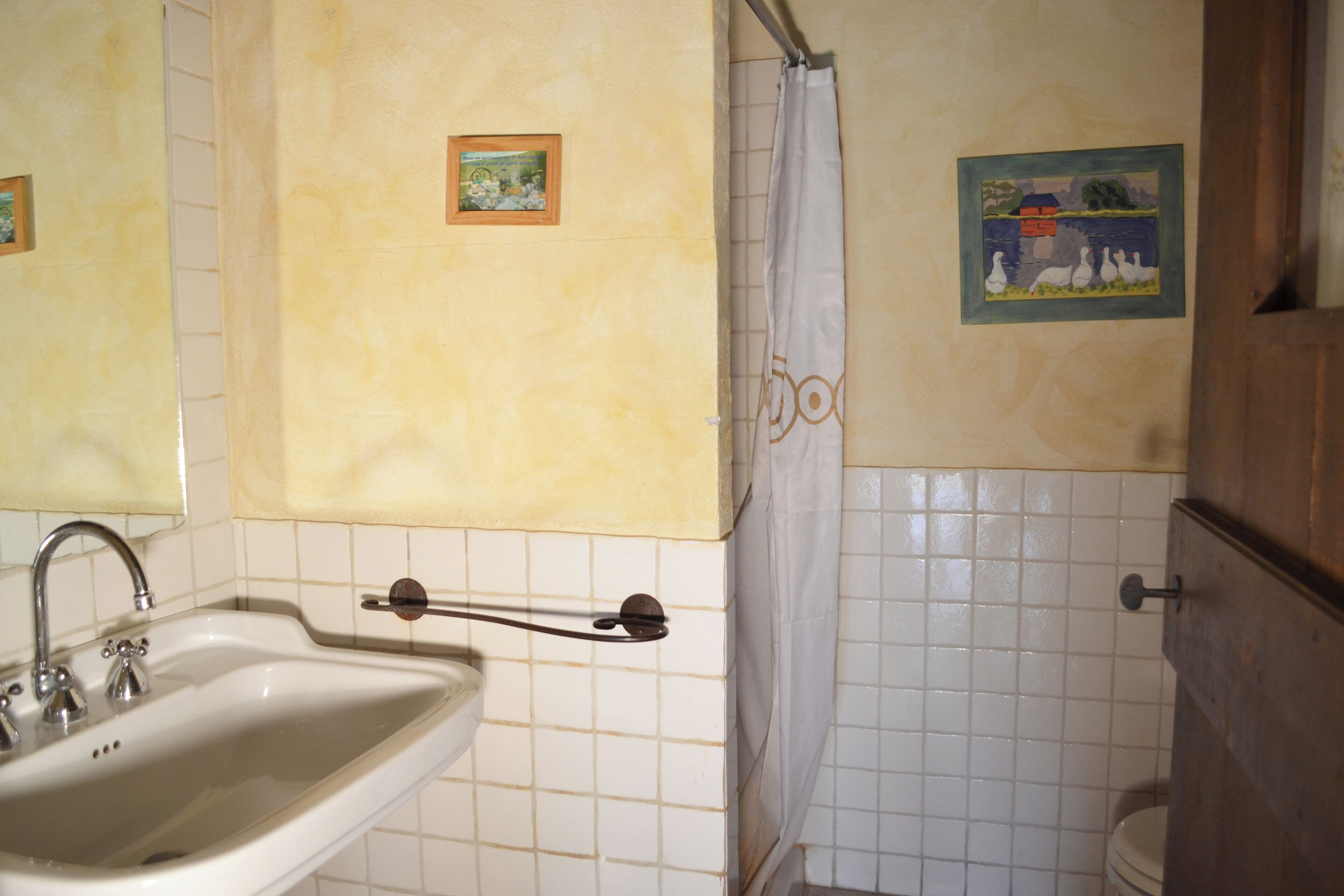 Ein Badezimmer mit Waschbecken, Duschvorhang und zwei gerahmten Bildern an der Wand.