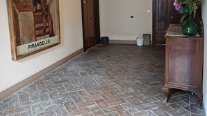 A spacious hallway with a tiled floor, a wooden door, and a framed artwork on the wall.