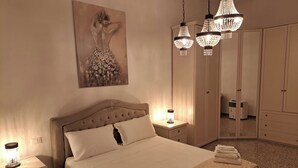 A bedroom with a large bed, a nightstand with a lamp, a wardrobe, and a painting on the wall.