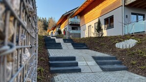 A modern building with a wooden facade and a stone pathway leading to the entrance. - Modernes Chalet in Hahnenklee (Goslar)