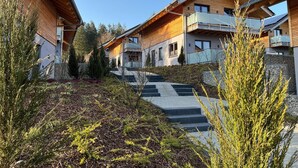 A modern building with wooden exterior and balconies, surrounded by landscaped garden and steps leading up to the entrance. - Modernes Chalet in Hahnenklee (Goslar)
