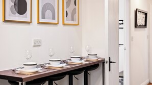 A dining area with a long table set for four, featuring black barstools and white plates with black stripes. - The Hallmark 3BR Apt JQ Birmingham, Parking & WiFi (Birmingham)
