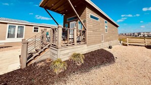 Une maison en bois d’un seul étage, avec un toit en pente, une véranda couverte dotée d’une balustrade et une allée gravillonnée.