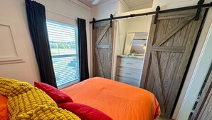Une chambre à coucher avec un lit, une porte coulissante en bois et une fenêtre avec des stores.