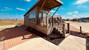 Un petit bâtiment en bois doté d’un escalier, d’une zone abritée et d’un chemin piétonnier dallé.