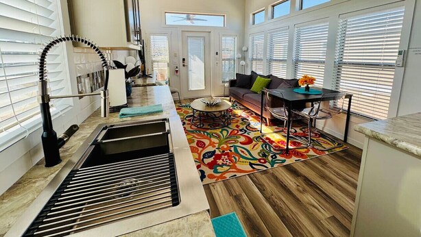 Une cuisine équipée d’un barbecue intégré, un coin repas avec une table et des chaises, et un tapis aux couleurs vives.