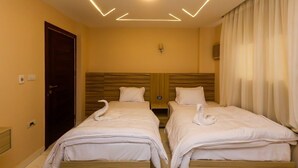 A hotel room with two beds, a wooden headboard, a wall-mounted light fixture, and a door. - kings pyramids view inn (Giza)