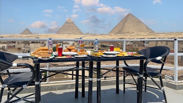 A table set with food and drinks on a balcony with views of the pyramids. - kings pyramids view inn (Giza)
