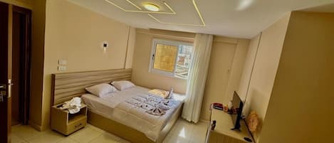 Un dormitorio moderno con cama, mesitas de noche, una ventana con cortinas e iluminación geométrica en el techo.