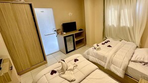 A hotel room with two beds, a television, a minibar, and a door. - kings pyramids view inn (Giza)