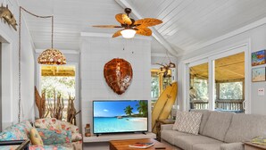 Un salon équipé d’un téléviseur, d’un ventilateur de plafond, d’un canapé et d’une table basse.