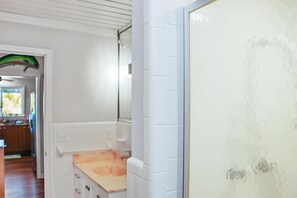 Una cocina con armarios blancos, una encimera y una puerta con panel de vidrio esmerilado.