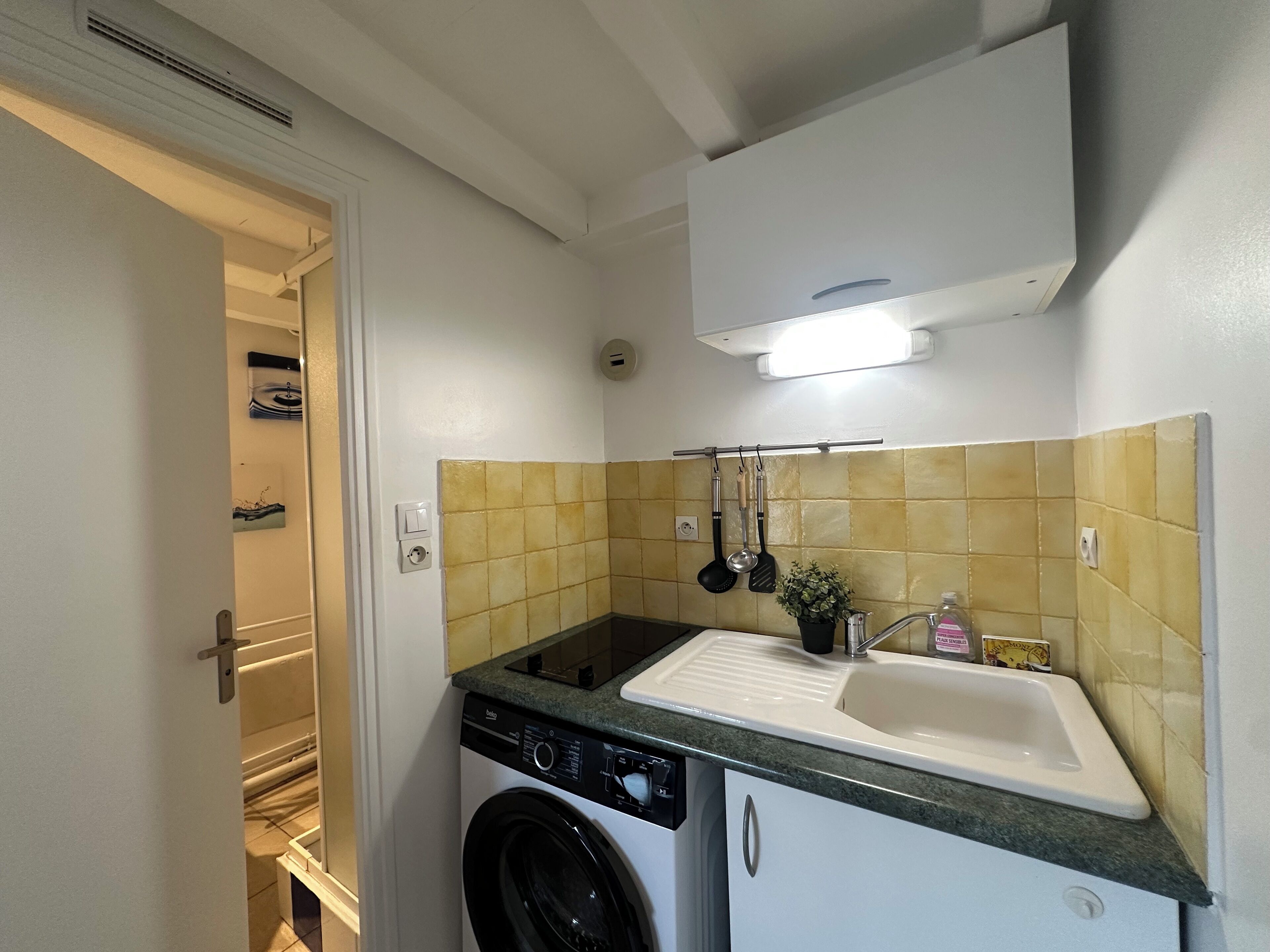 A compact kitchen with a washing machine, a sink, and a small countertop.