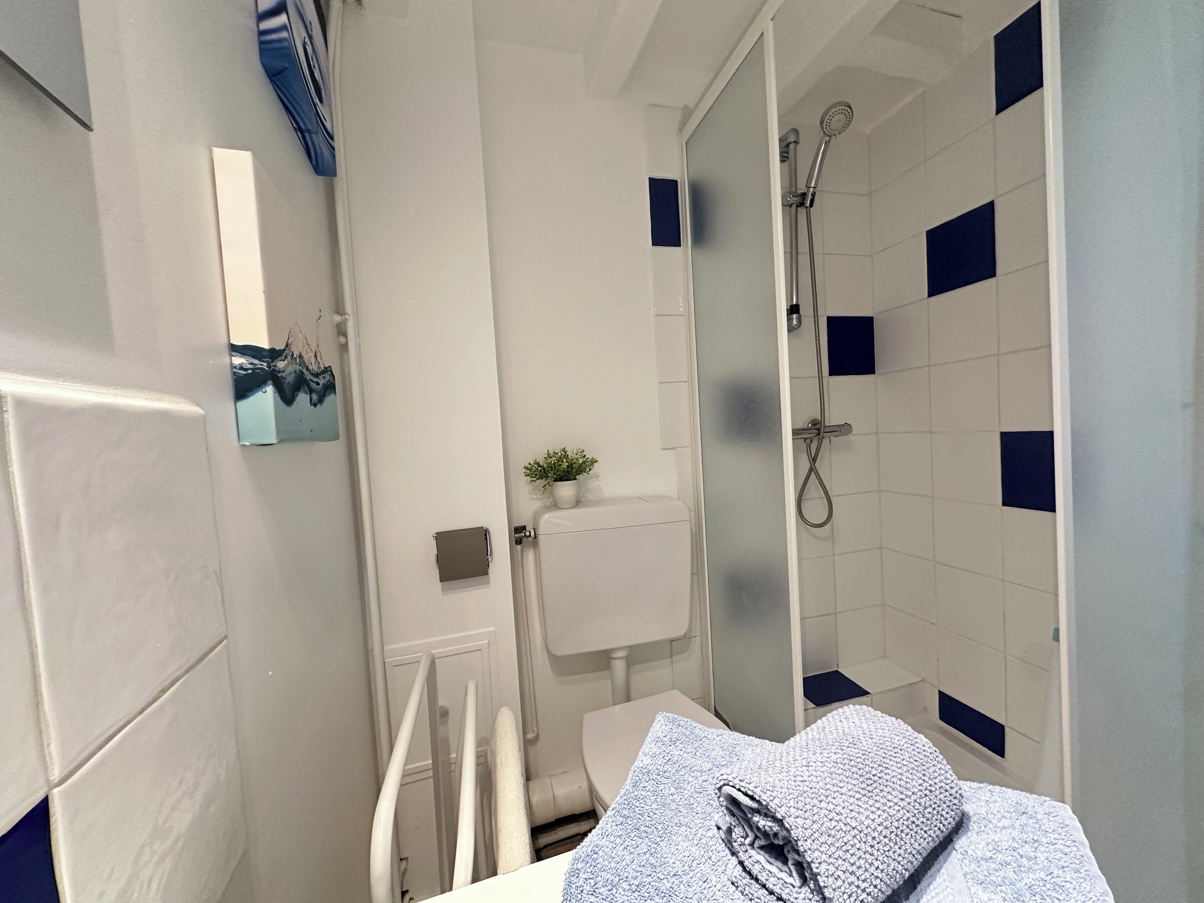 Et badeværelse med toilet, bruser og et håndklæde på bordet.