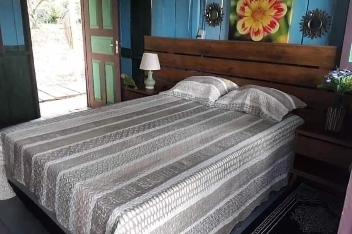 Une chambre à coucher avec un lit, une table de chevet, une lampe et un tableau au mur.