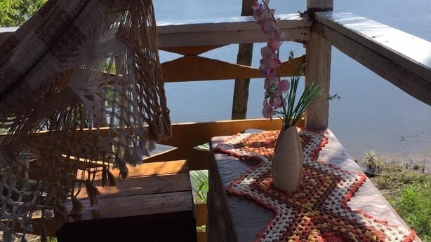 En træterrasse med en hængekøje, en bordløber med krogroser, og en potteplante.