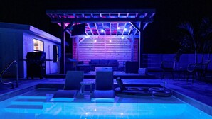 An outdoor pool area with lounge chairs and a covered seating area.