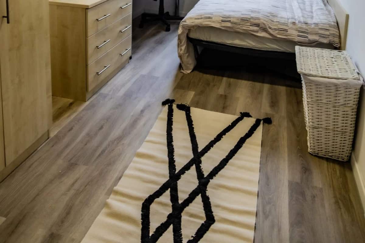 A compact bedroom with a bed, desk, chair, and a small window.