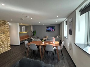 Meetings and relaxation come together in this well-designed space with a conference table, comfortable seating, and a large TV.