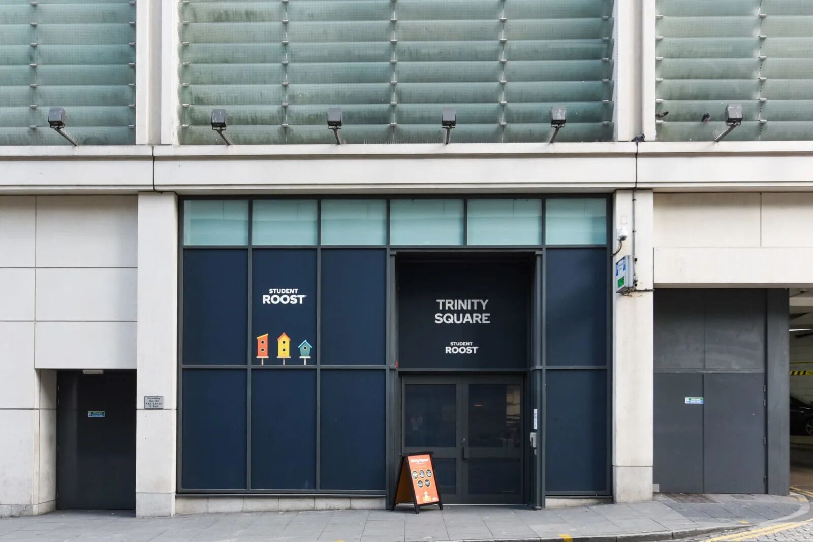 A building with large windows, labeled "Student Roost Trinity Square."