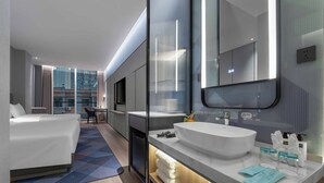 A modern hotel room with a large bed, a desk, a bathroom with a large mirror, and a view of the city. - Holiday Inn Express Harbin Central Avenue by IHG (Harbin)