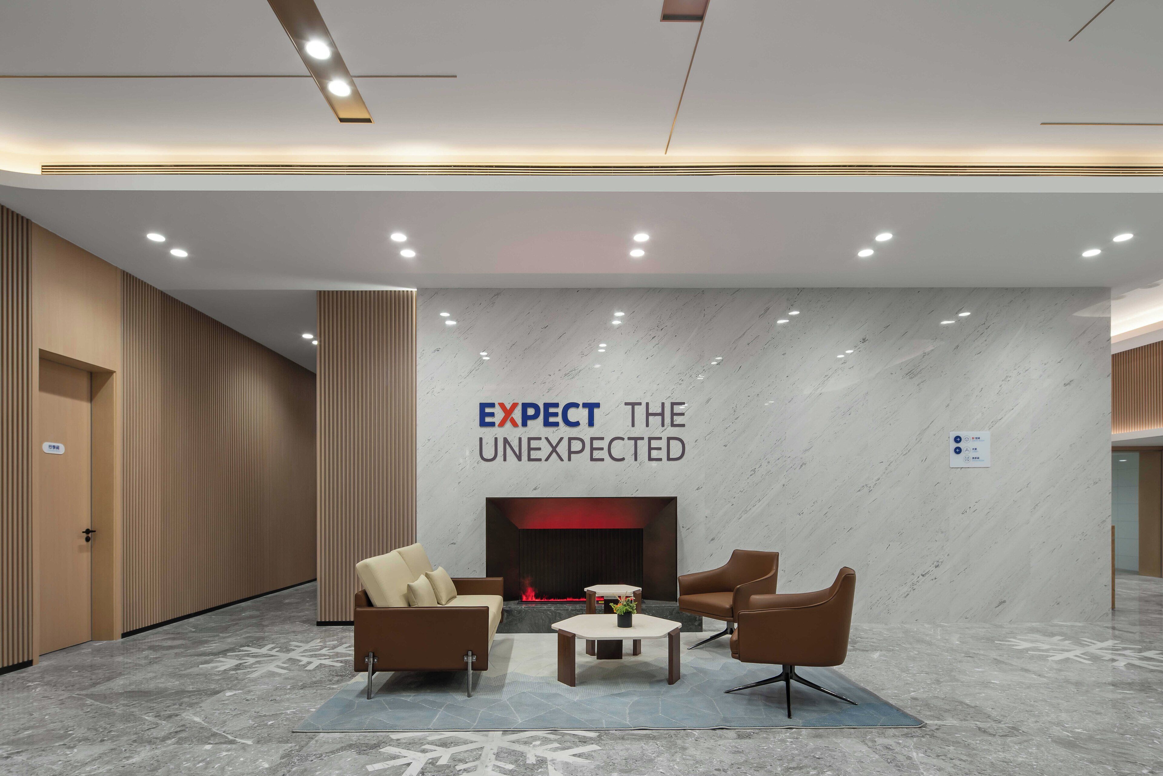 Un lobby moderno con chimenea, zona de estar y un letrero que dice "EXPECT THE UNEXPECTED".