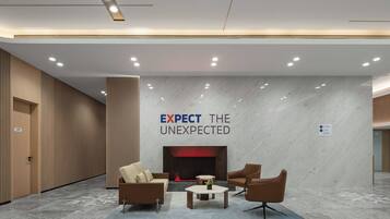 Un lobby moderno con chimenea, zona de estar y un letrero que dice "EXPECT THE UNEXPECTED".