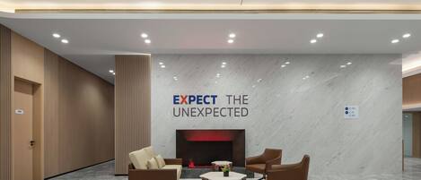Un lobby moderno con chimenea, zona de estar y un letrero que dice "EXPECT THE UNEXPECTED".
