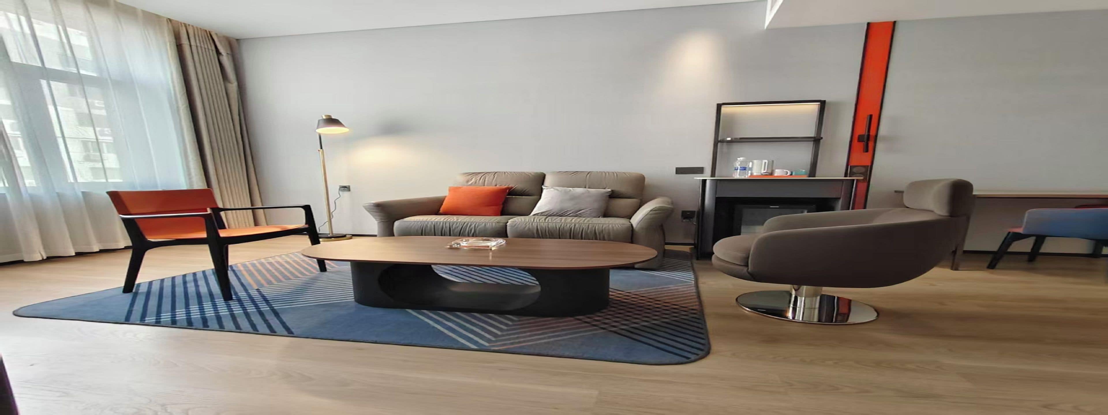 Una sala de estar moderna con un sofá, dos sillones, una mesa baja y una chimenea.