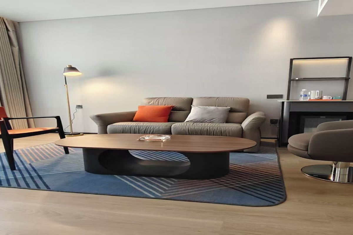 A modern living room with a sofa, two armchairs, a coffee table, and a fireplace.