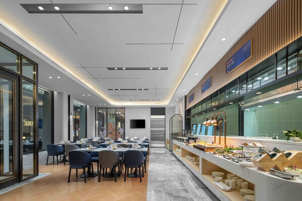 A modern dining area with tables and chairs, a buffet counter, and a large window. - Holiday Inn Express Harbin Central Avenue by IHG (Harbin)