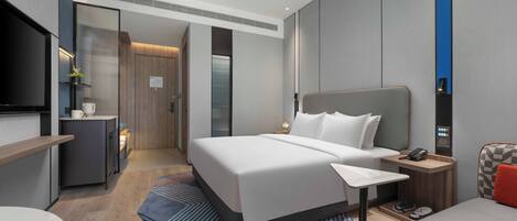A modern hotel room with a large bed, bedside table, and a TV.