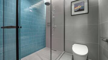 Un baño moderno con cabina de ducha de vidrio, un inodoro y un cuadro en la pared.