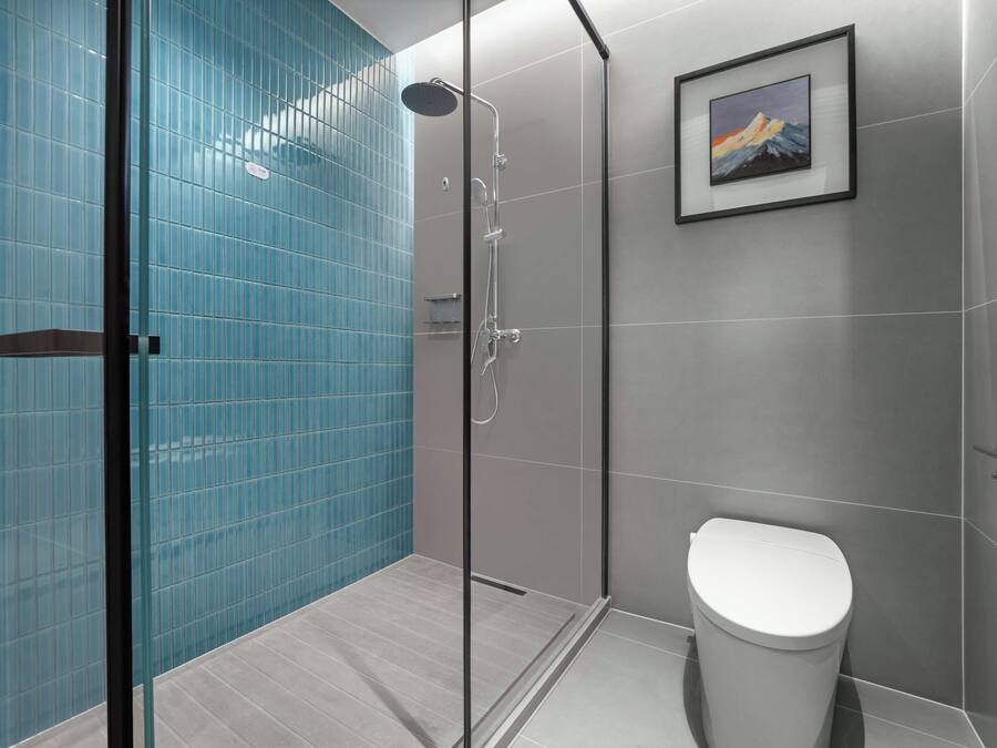 Un baño moderno con cabina de ducha de vidrio, un inodoro y un cuadro en la pared.