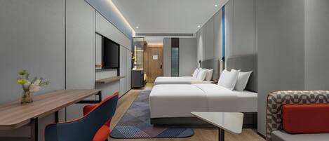 A modern hotel room with a bed, a sofa, a desk, and a TV.