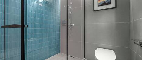 A modern bathroom with a glass shower enclosure, a white toilet, and a framed painting on the wall.