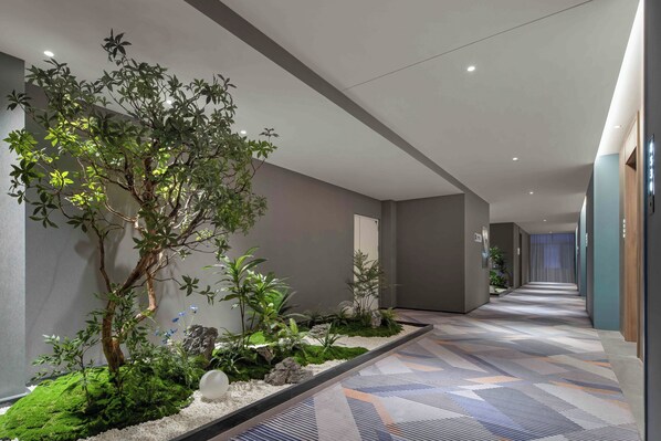 A modern hotel corridor with a central garden, neutral walls, and patterned carpet. - Holiday Inn Express Harbin Central Avenue by IHG (Harbin)