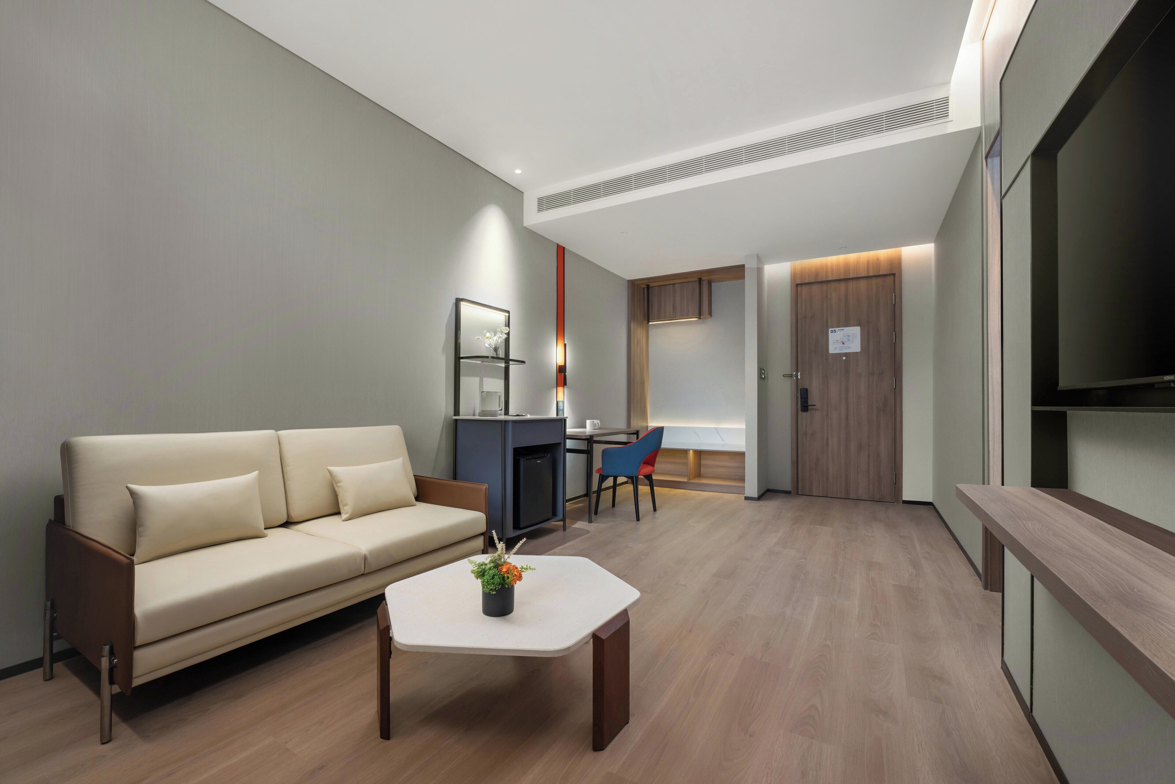 A modern living room with a sofa, a coffee table, and a dining area with a chair and table.