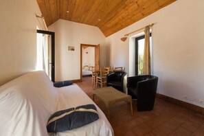Cozy retreat with a bed, wooden table, and woven ottoman.
