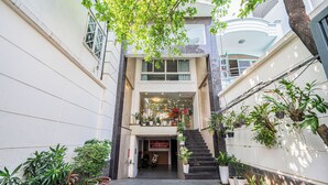 A narrow, covered walkway with potted plants on either side, leading to a building entrance with a staircase. - Cozrum - Love Hotel Trần Bình Trọng (Ho Chi Minh City)