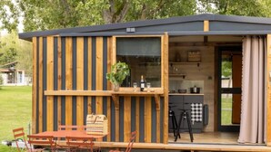 A wooden cabin with a dining area, kitchen, and a sliding door. - ZEcamping 3* animaux acceptés piscine et restaurant (Saintes)