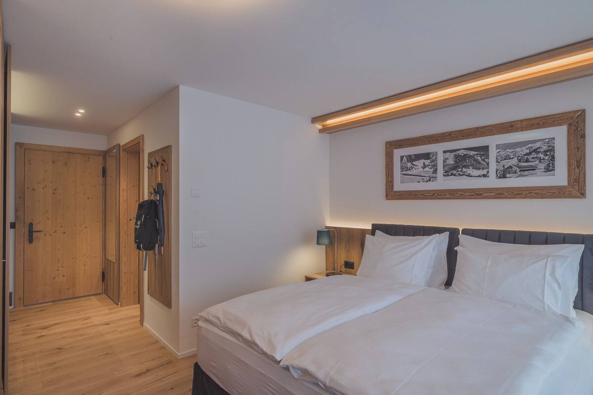 A bedroom with a bed, wooden wardrobe, and a wall-mounted picture frame.
