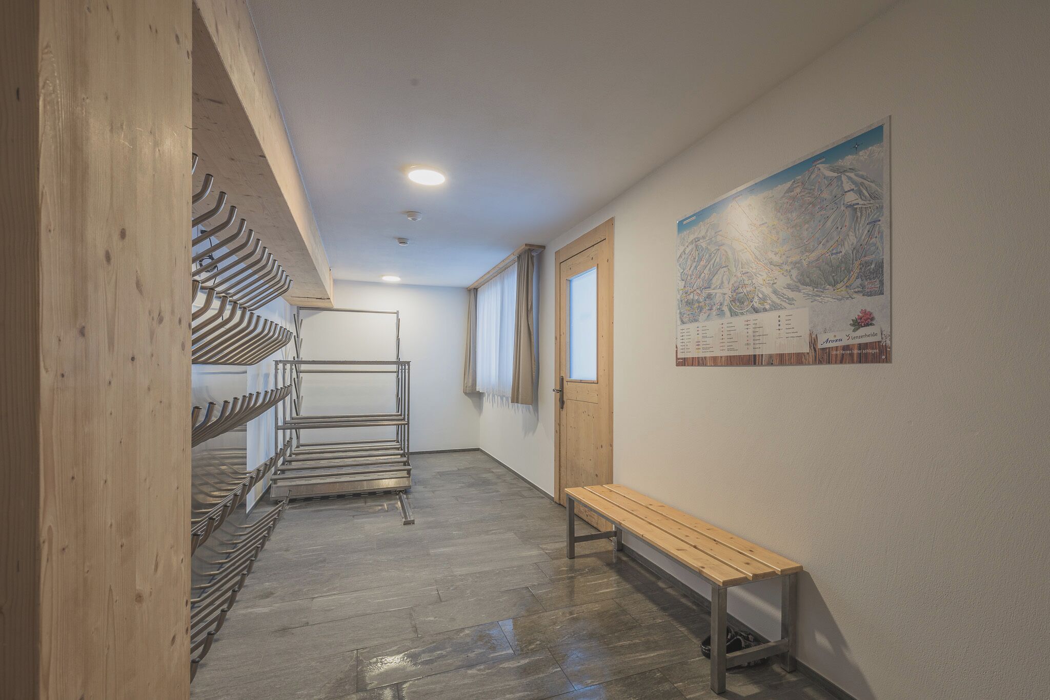 A hallway with a wooden bench, metal storage racks, and a wall-mounted map.