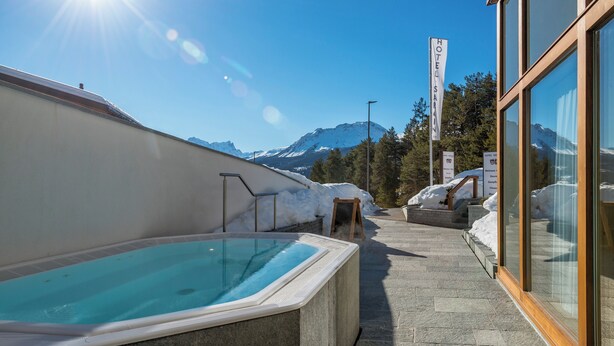 A hot tub area with a mountain view, a wooden bench, and a sign for the hotel. - Val Saraina Resort Apartments Lenzerheide (Lantsch-Lenz)