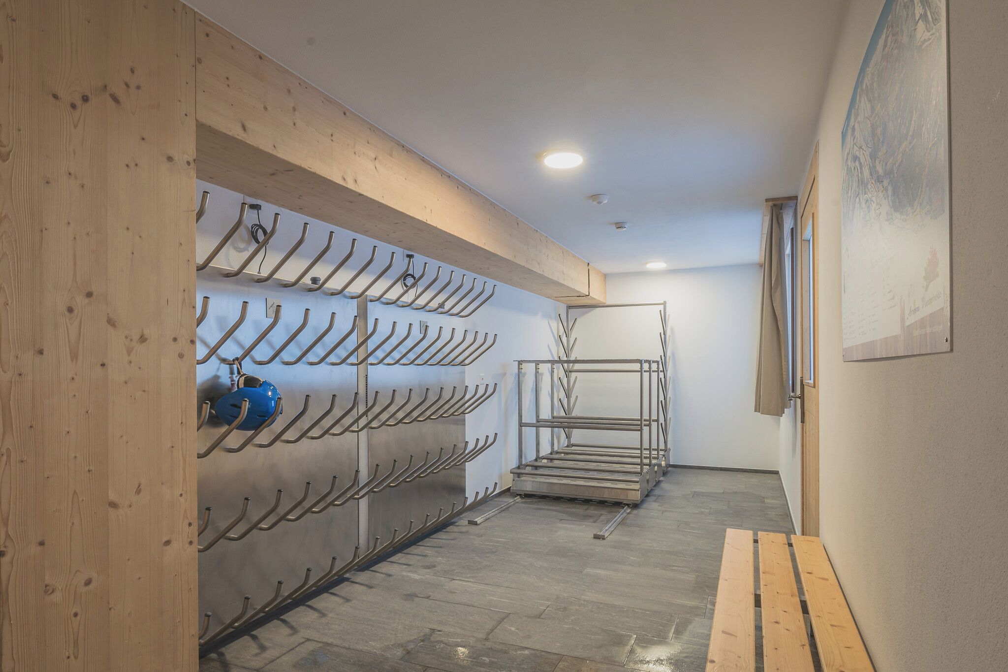 A hallway with a wooden wall, metal coat hooks, and a metal rack.