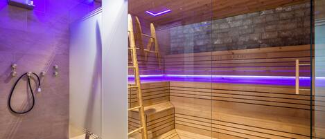A modern bathroom with a glass shower enclosure, wooden steps, and a visible brick wall.